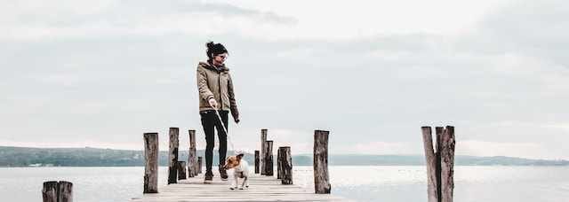 Woman walking dog on boardwalk in cold weather