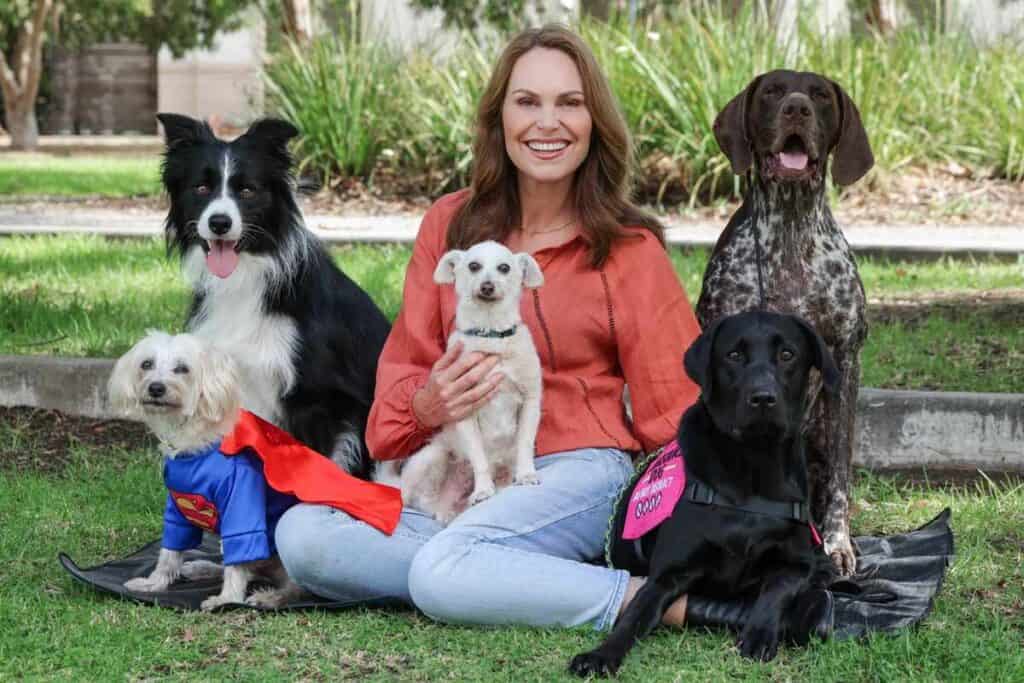 Dog expert Lara Shannon and five dogs sit on grass to promote new show searching for the best dogs in Australia: The Dog Down Under